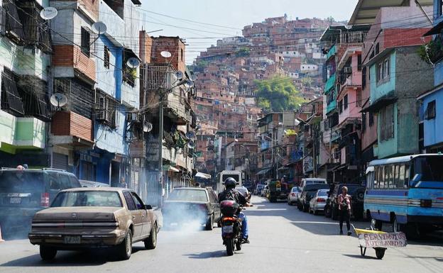 Imagen principal - Arriba, una vista del cerro José Félix Ribas, una de las favelas más grandes de América Latina. A la izquierda, Enrique, cuñado. A la derecha, un vecino. 