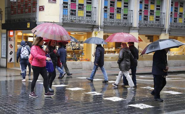 Varias personas se tapan de la lluvia con un paraguas en los Cuatro Cantones.