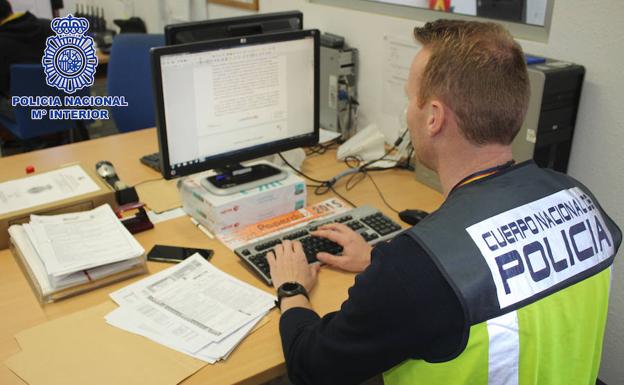 Un policía nacional trabaja con un ordenador.