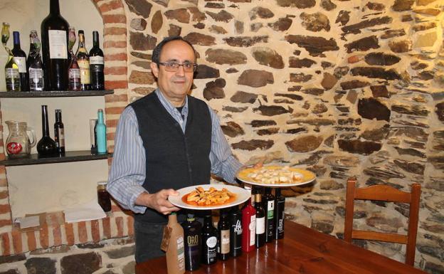El propietario del establecimiento, Santos Yagüe, posa con dos platos de escabechados y su colección de aceites. 