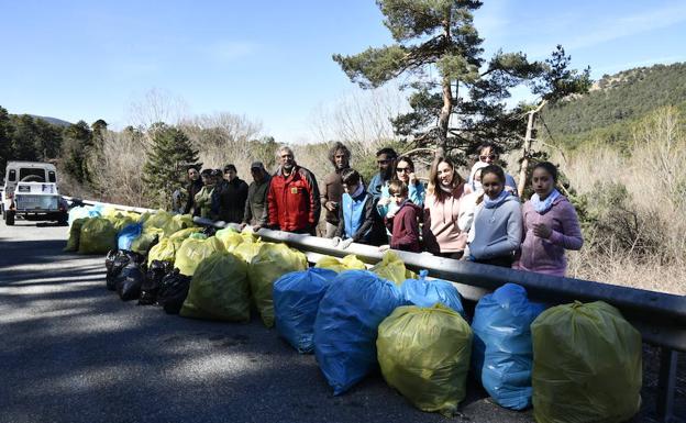 Participantes en la recogida posan, junto a la carretera, con las bolsas que llenaron. 