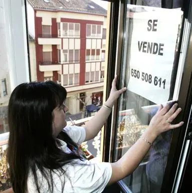Una mujer coloca un cartel en una ventana.