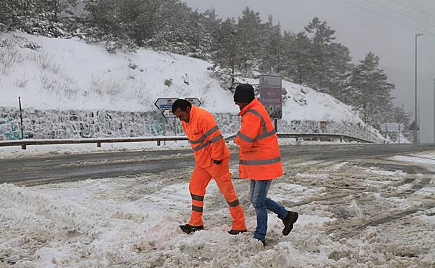 Dos hombres se protegen del intenso frío mientras caminan sobre la nieve, ayer en Navacerrada. 