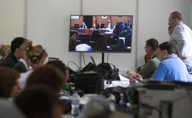 Los periodistas siguen la vista a través de una pantalla. 