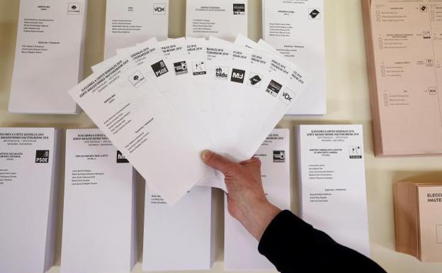 Una persona muestra en las papeletas las diferentes opciones políticas que tendrán los electores hoy.
