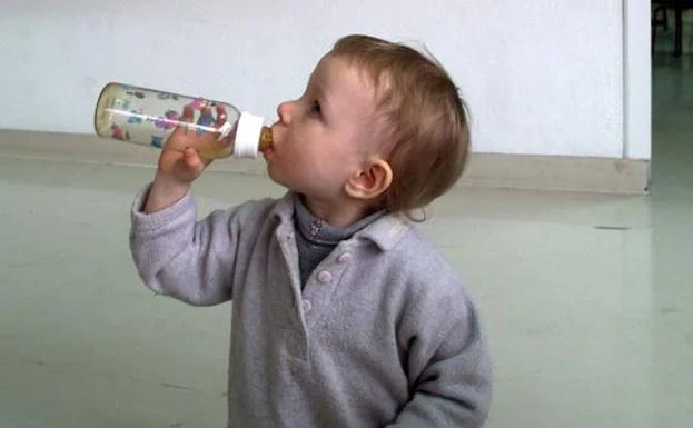Un bebé, con su biberón. 