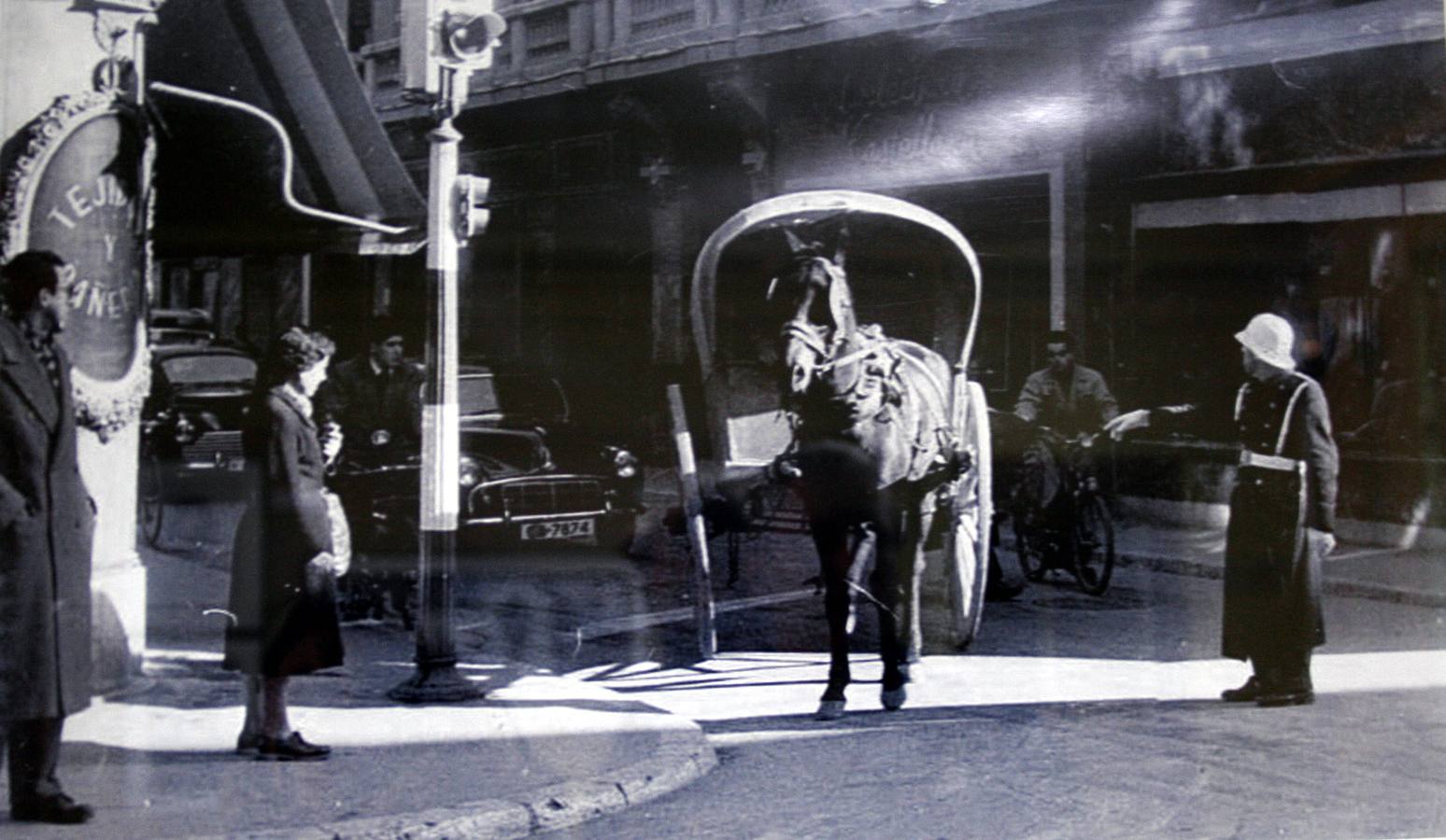 Fotografia de los años 50 en la que se ve como un guardia municipal para un carro en la calle Regalado.