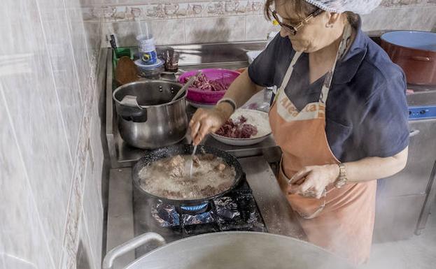 Adela Calleja prepara un caldo de pollo en una gran cazuela para los comensales del día. 