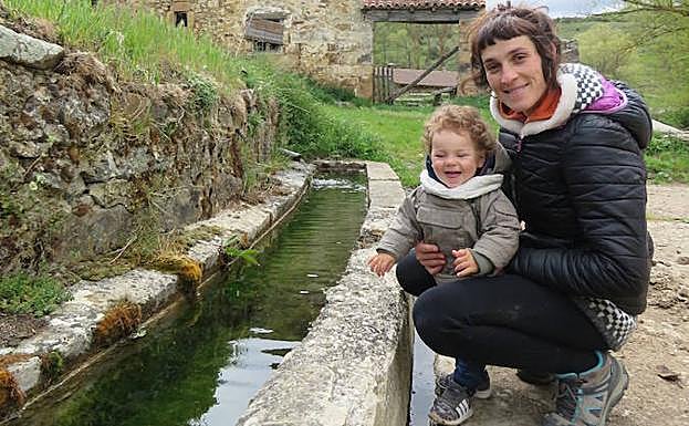 Zaida Largo, junto a su hijo Mauro en el pilón que tienen al lado de su casa en Celada de Roblecedo. 