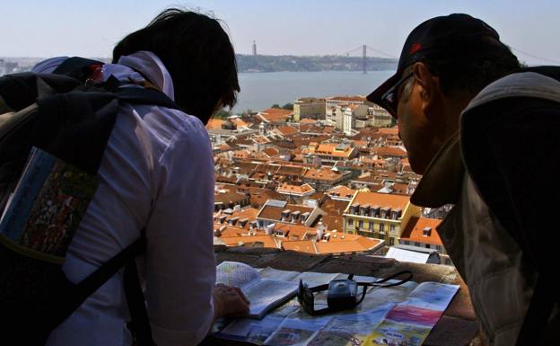 Turistas consultan un papa en el Castillo de San Jorge de Lisboa.