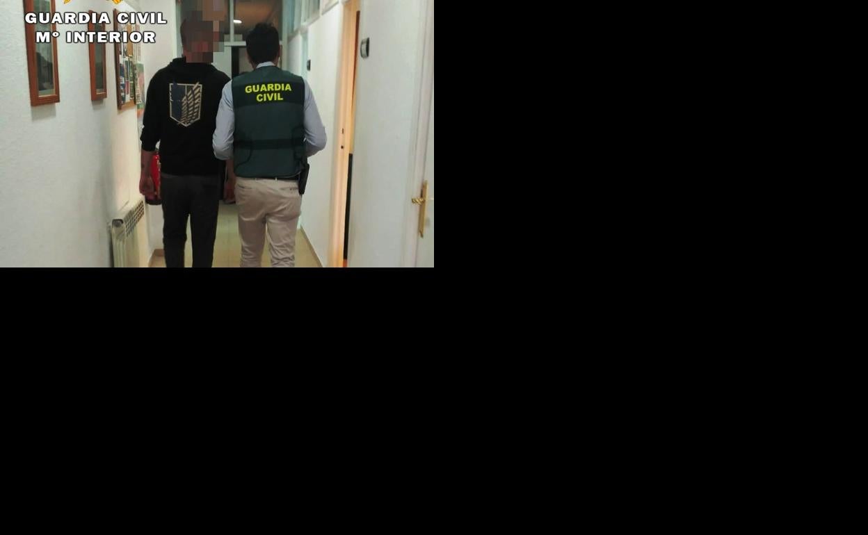 El detenido es conducido por un miembro de la Guardia Civil en el Puesto de Arévalo