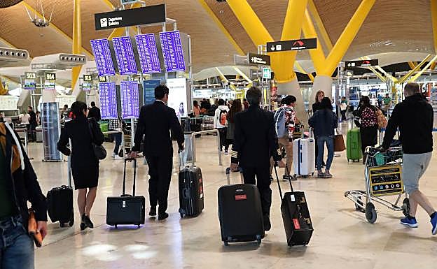 Varios viajeros en el aeropuerto internacional de Madrid-Barajas se dirigen hacia sus vuelos.