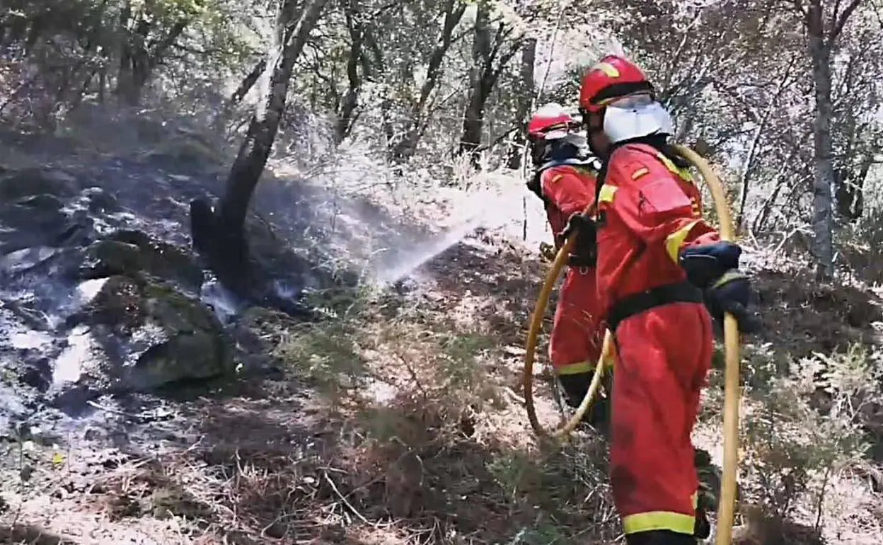 Dos bomberos sofocan un foco del incendio en Cadalso de los Vidrios. 