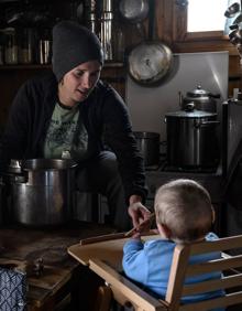 Imagen secundaria 2 - La joven posa en el umbral de la puerta del albergue, en el que recibe a los excursionistas durante los meses de verano. La guardesa juega con su hijo Armand en la cocina del refugio, donde prepara el desayuno y la cena para los alpinistas que paran allí. El refugio no tiene electricidad ni agua corriente. El baño se encuentra fuera. 