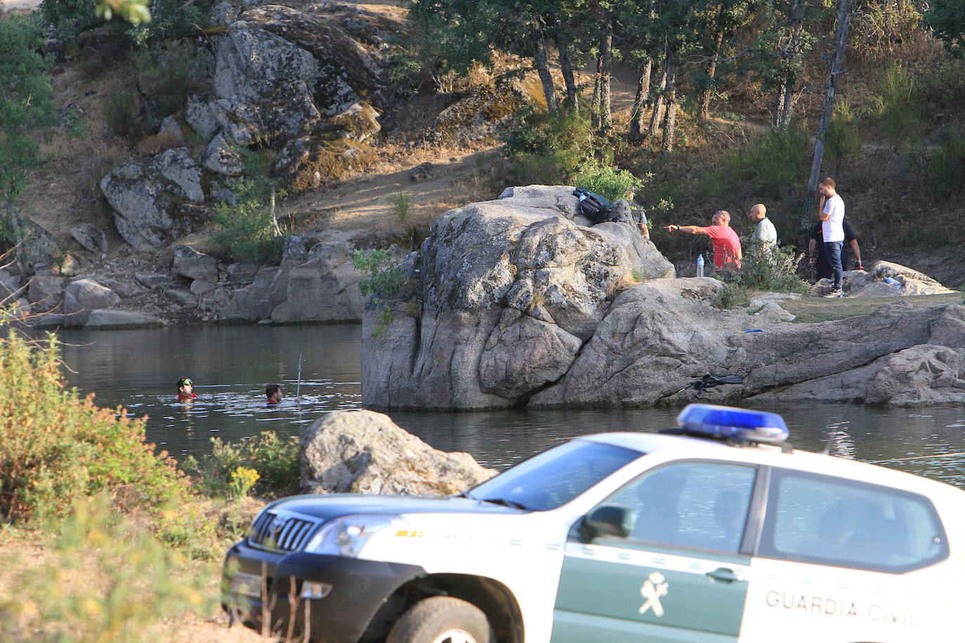 Buzos inspeccionan el agua junto a la roca desde la que saltó el menor. 