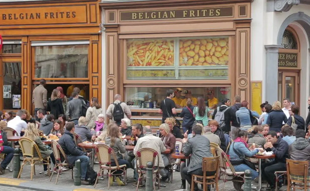 Clientes degustan 'frites' en la terraza de un establecimiento especializado de Bruselas.