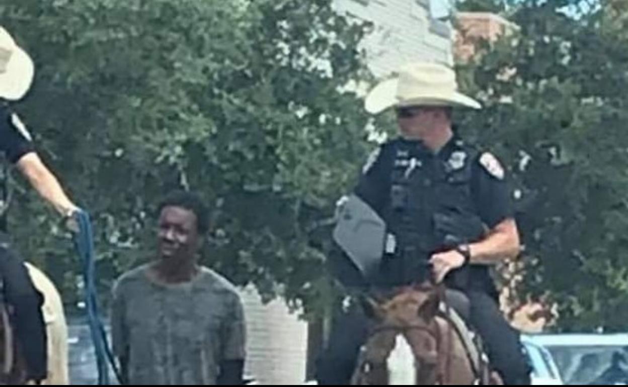 Dos policías a caballo llevan a un hombre negro esposado y atado con una cuerda en Estados Unidos