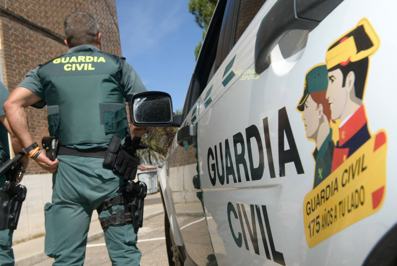 Un agente de la Unidad de Seguridad Ciudadana, junto al vehículo de la Guardia Civil. 