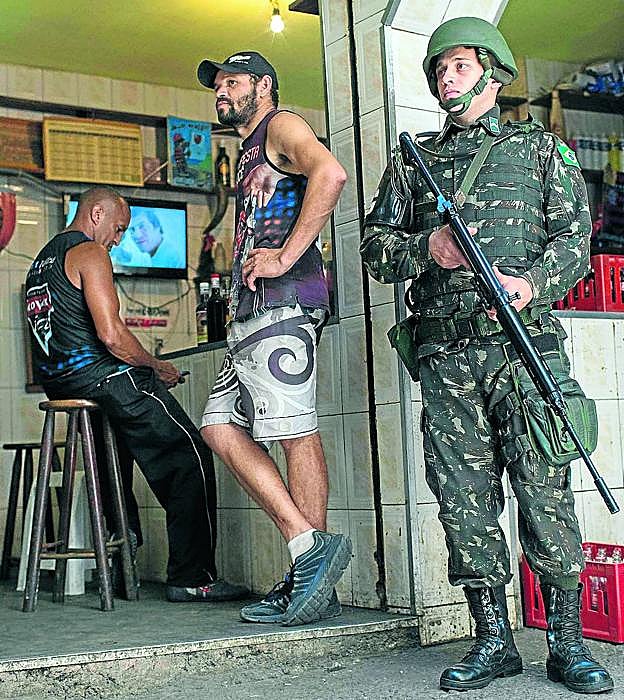 Imagen principal - Postales.  Soldados brasileños patrullando por Rocinha. Un niño jugando al balón. Vista de la favela. 