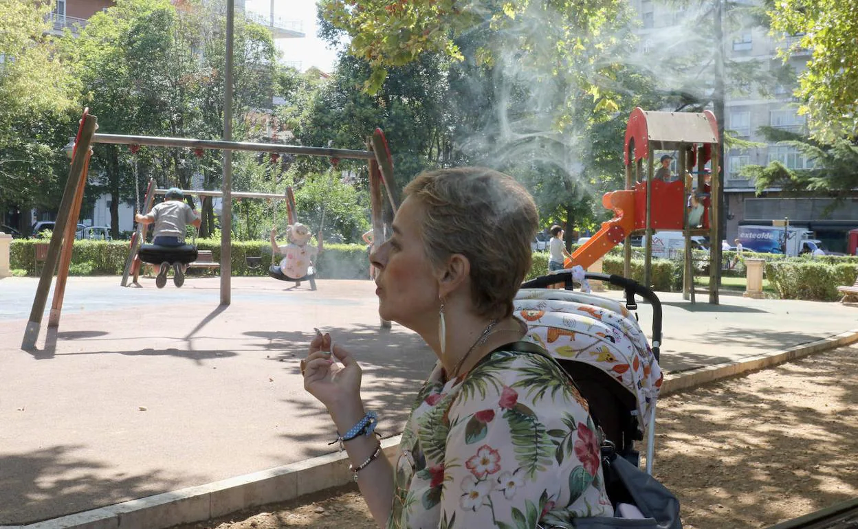 Una mujer fuma junto a la zona de juegos en Poniente. 