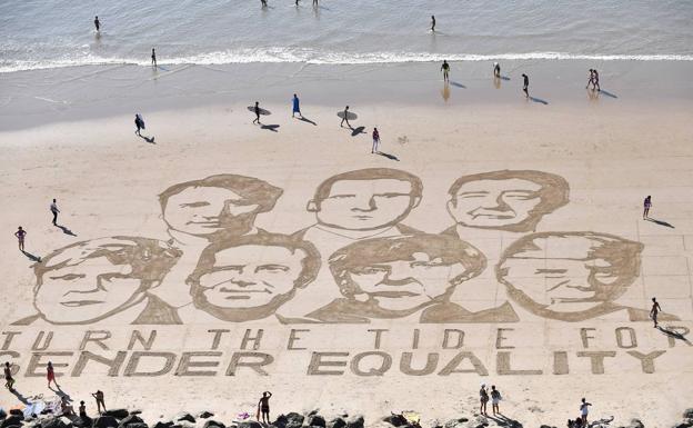 Vista aérea de un mensaje escrito en la arena por el artista francés Sam Dougados, en el que ve los rostros de los líderes de los países del G7 junto al mensaje «Que cambie la marea por la igualdad de género» en la playa de la Côte des Basques en Biarritz. 