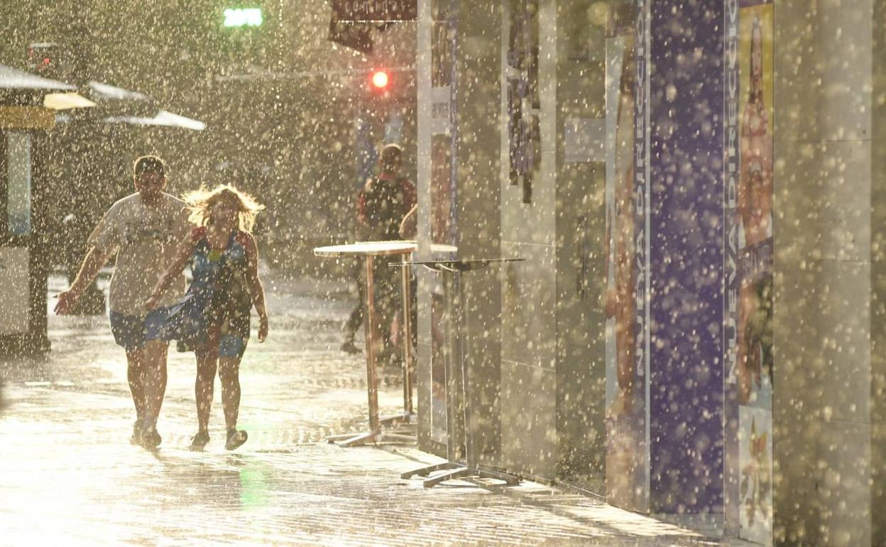Varios peatones, bajo la lluvia en Valladolid. 