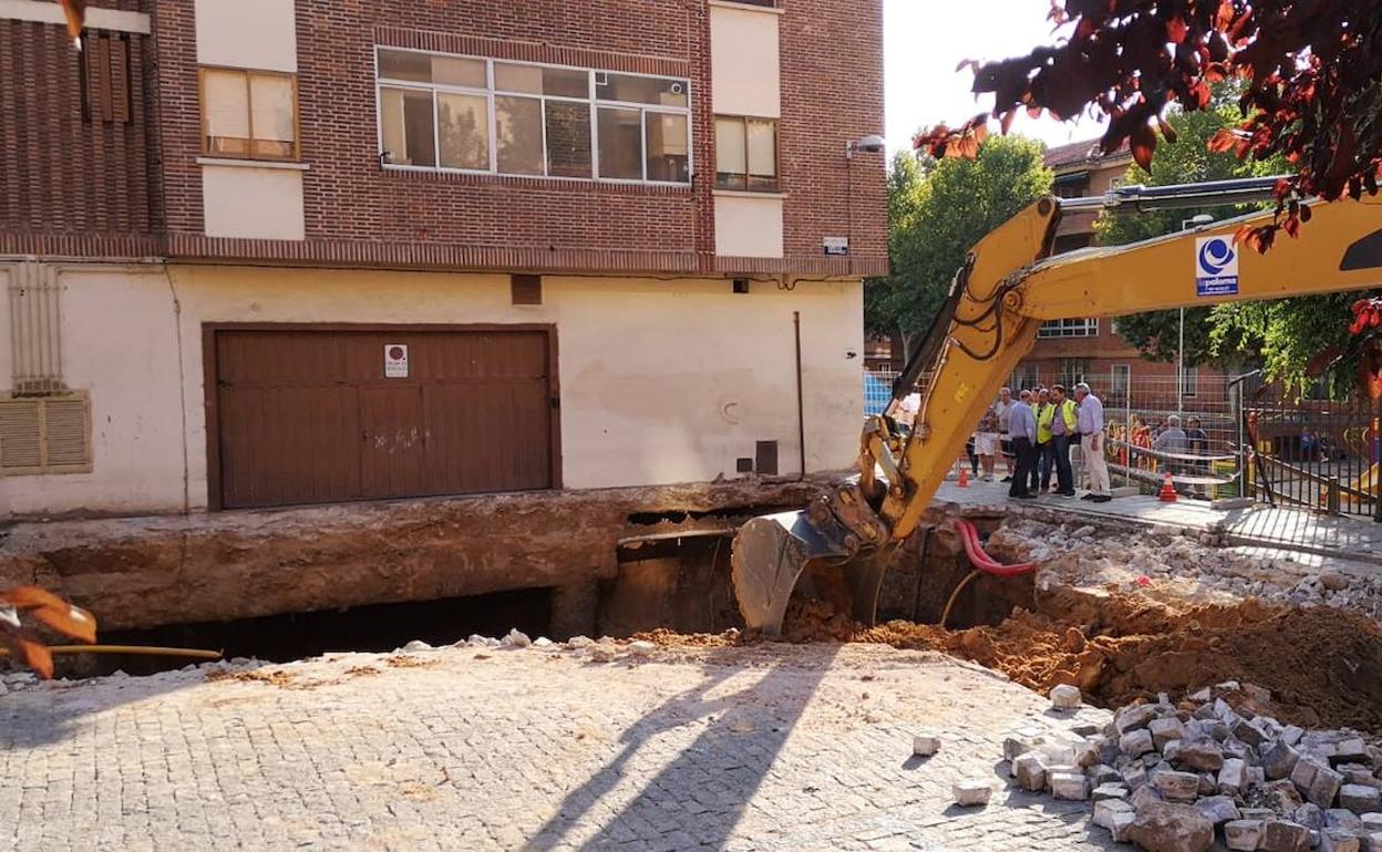 Una excavadora trabaja en el socavón para asegurar los bordes y hacer una rampa de acceso.