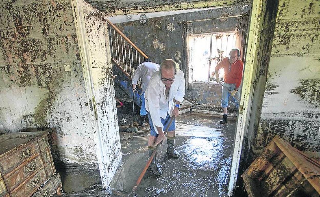 Vecinos de Las Navas del Marqués limpian sus viviendas llenas de barro y lodo. 