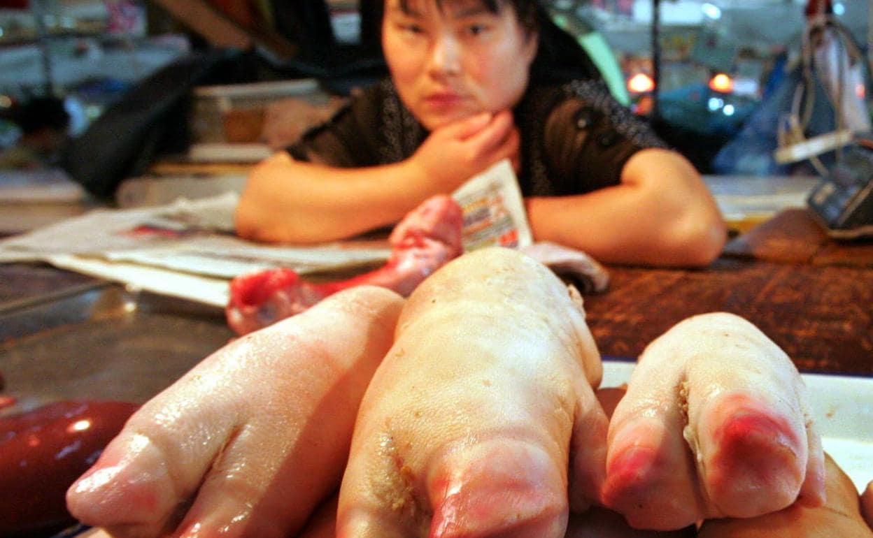 Una vendedora de pezuñas de cerdo esperando clientes en un mercado de Pekín. 