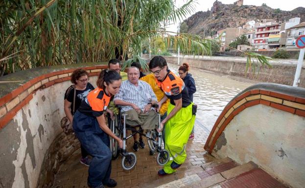 Galería. Voluntarios de protección civil trasladan a un hombre en silla de ruedas tras las intensas lluvias en Blanca (Murcia).