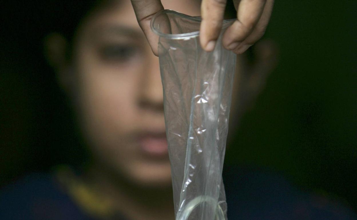 Una joven posa con un preservativo. 