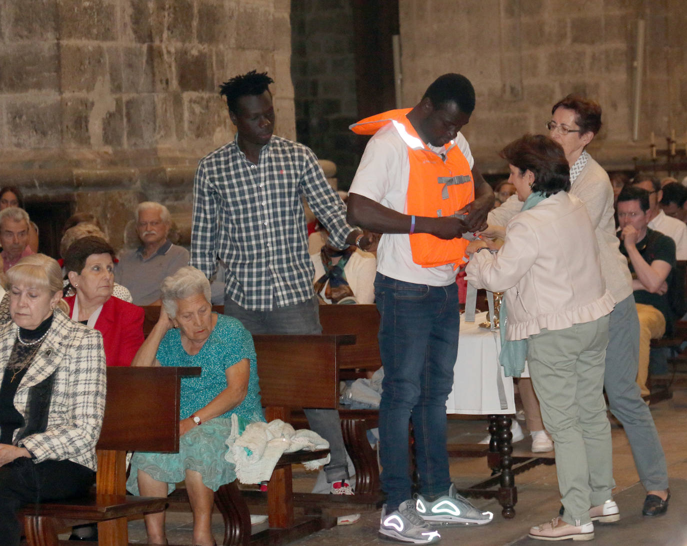 Luis Argüello saluda a varios jóvenes inmigrantes junto a la Cruz de Lampedusa. 