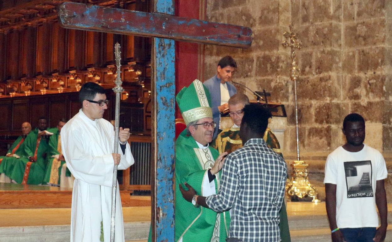 Luis Argüello saluda a varios jóvenes inmigrantes junto a la Cruz de Lampedusa. 