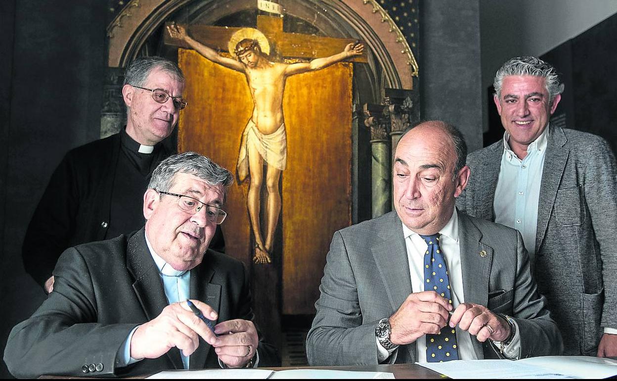 El vicario general, Ángel Galindo, y el presidente de la Diputación, Miguel Ángel de Vicente, firman delante del Cristo de Berruguete. 