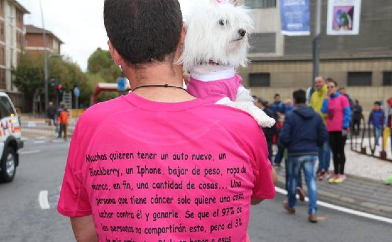 Una mujer, junto a su perro, participan en la carrera de la mujer.