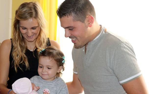 La pequeña Cataleya juega con una muñeca en presencia de sus padres, Carlota y Adrián. 