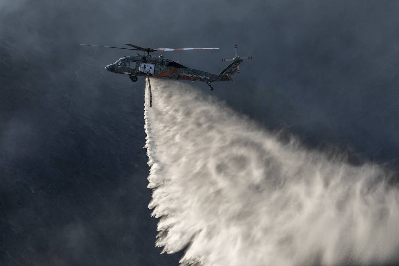 Un helicóptero de los bomberos descarga agua sobre las llamas del 'Getty Fire'