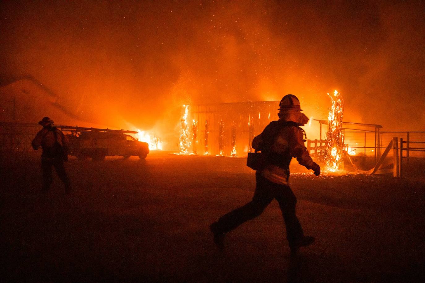 Bomberos frente a una granja en llamas durante el incendio Kincade