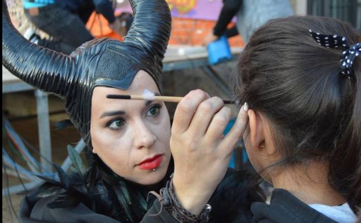 Maléfica maquilla a una niña en el taller de pintacaras de Halloween en Cigales.