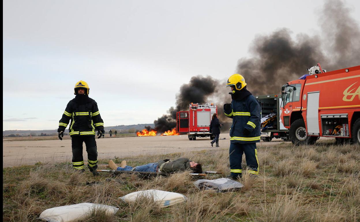 Los bomberos acompañan a uno de los participantes en el simulacro como heridos.