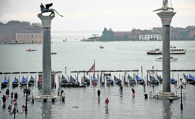 Los visitantes acceden a la ciudad entre las columnas de San Marco y San Teodoro, que en la imagen emergen del mar por efecto del 'agua alta'.