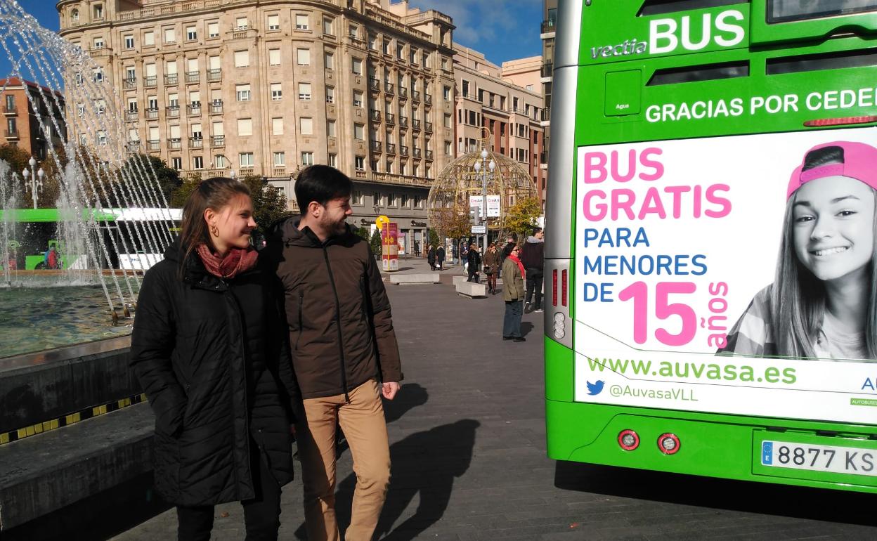 Dos jóvenes observan la publicidad del nuevo bono 15 en un autobús estacionado en Plaza Zorrilla. 