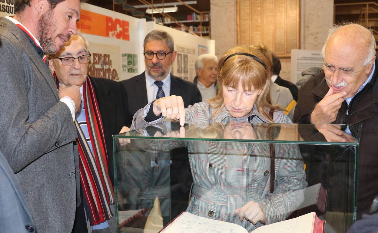 El alcalde y los visitantes a la muestra observan uno de los libros expuestos.