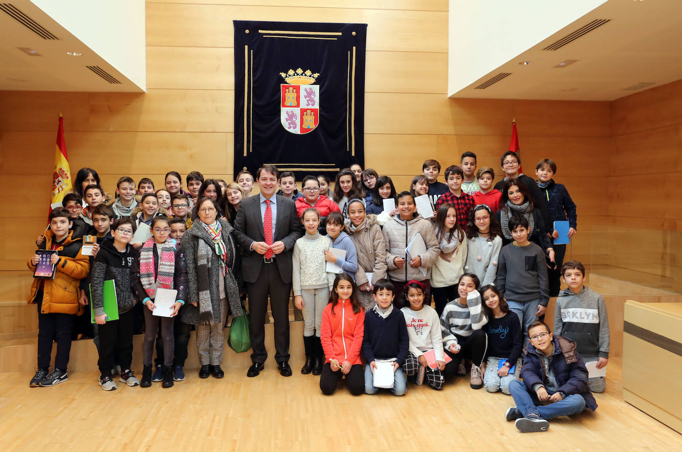 El presidente de la Junta, Alfonso Fernández Mañueco, conversa con un grupo de niños durante su visita a la sede del Parlamento Autonómico.