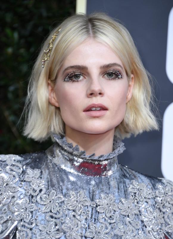 Lucy Boynton eligió un diseño plateado de lamé de Louis Vuitton. Tenía cuello victoriano, cinturón y bordados en cuerpo y mangas. A pesar de que el vestido tenía fuerza por sí solo, lo reforzó con un maquillaje fantasía y una horquilla dorada prendida de su melena.