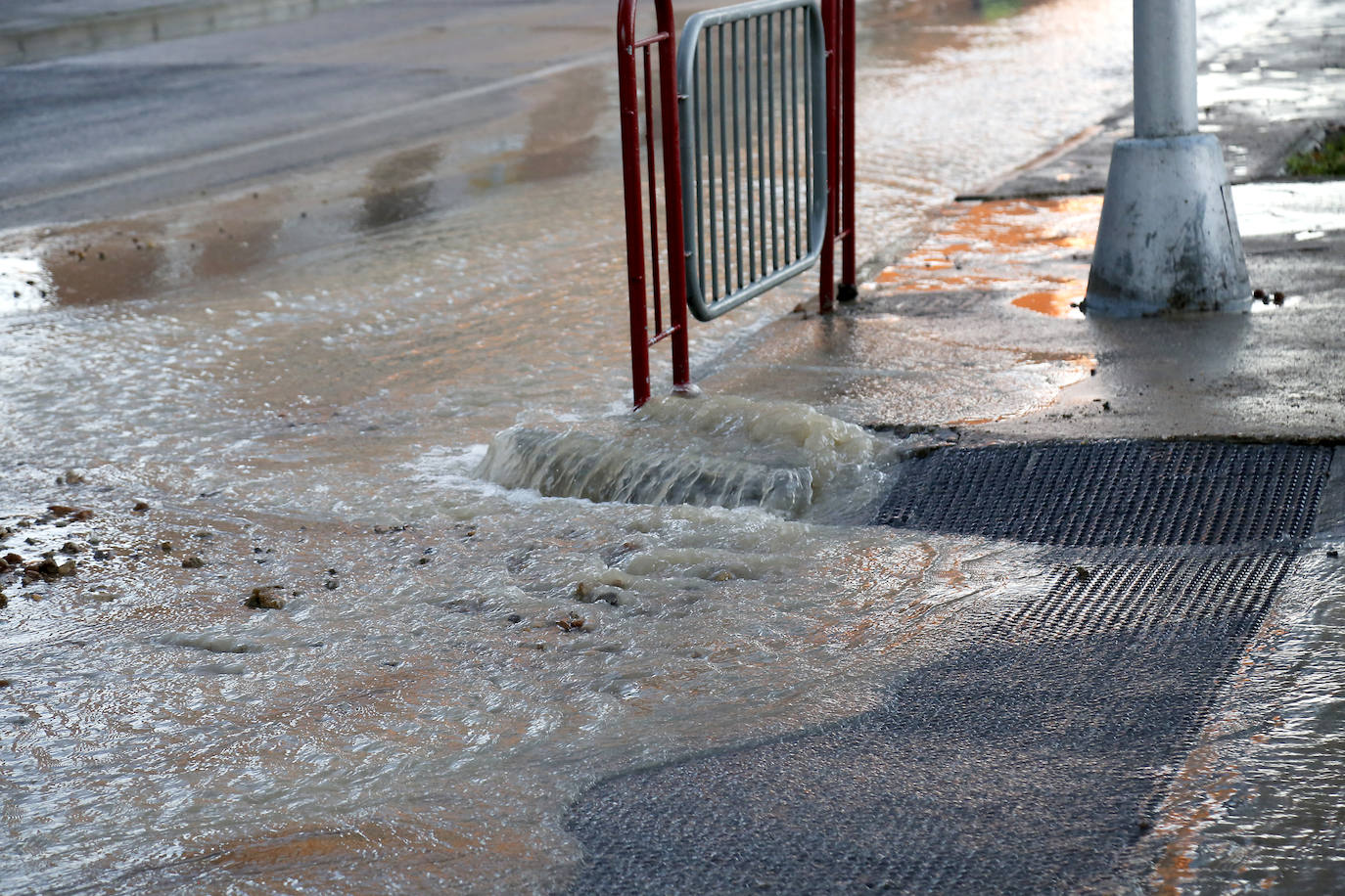 El agua sale con fuerza de una alcantarilla, en la avenida Reyes Católicos. 