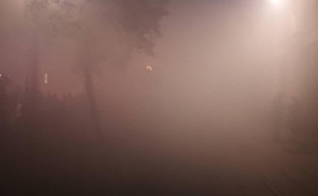 Acera de Recoletos, a la derecha. Motos con antorchas, a la izquierda. Se intuyen las siluetas de unos árboles y algunas personas entre el humo y la niebla. Foto sin filtros ni tratamiento. 