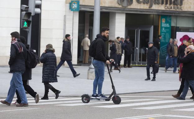 Un joven cruza con un patinete eléctrico por un paso de peatones de la Plaza de Zorrilla. 