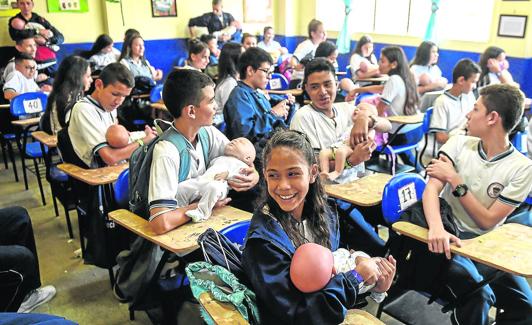 Adolescentes colombianos participan en un programa con bebés-robot.AFP