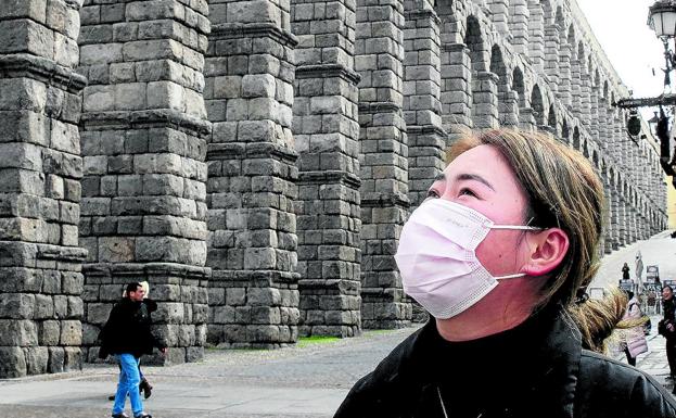 Una turista china provista de mascarilla contempla el Acueducto de Segovia. 